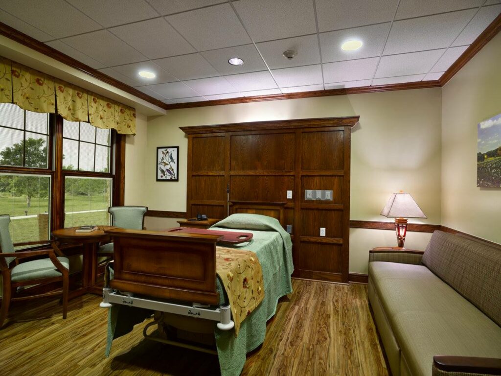 Comfortable patient room with a bed, seating, and large windows.