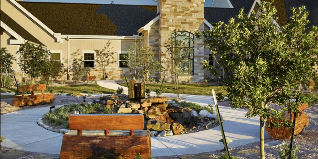 Peaceful garden area with wooden benches and a stone water feature.