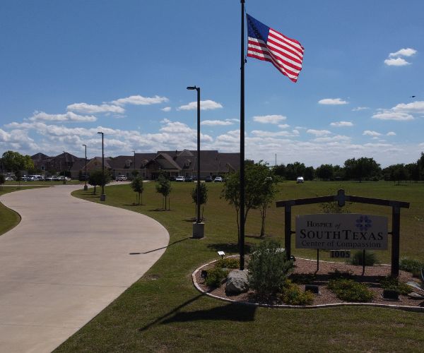 Entrance of Hospice of South Texas with an American flag and sign.