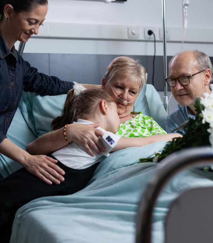 Family gathered around a patient in a hospital bed.